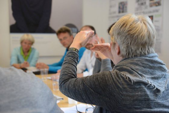 Eine Gruppe Menschen sitzt um einen Tisch herum und diskutiert.