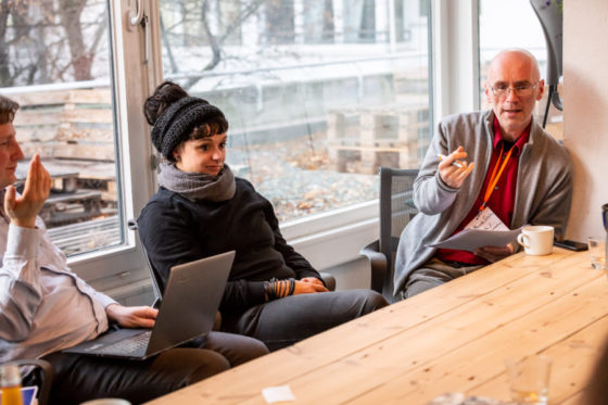 Ein Mann sitzt neben einer Frau am Tisch und spricht.