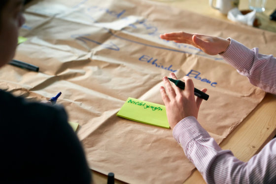 Eine Hand schreibt auf einem großen Stück Packpapier
