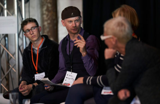 Ein Mann sitzt zwischen drei Zuhörerinnen.