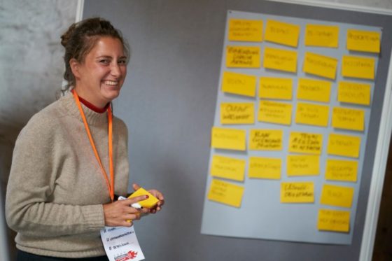 Ein Frau steht lachend vor einer Flipchart