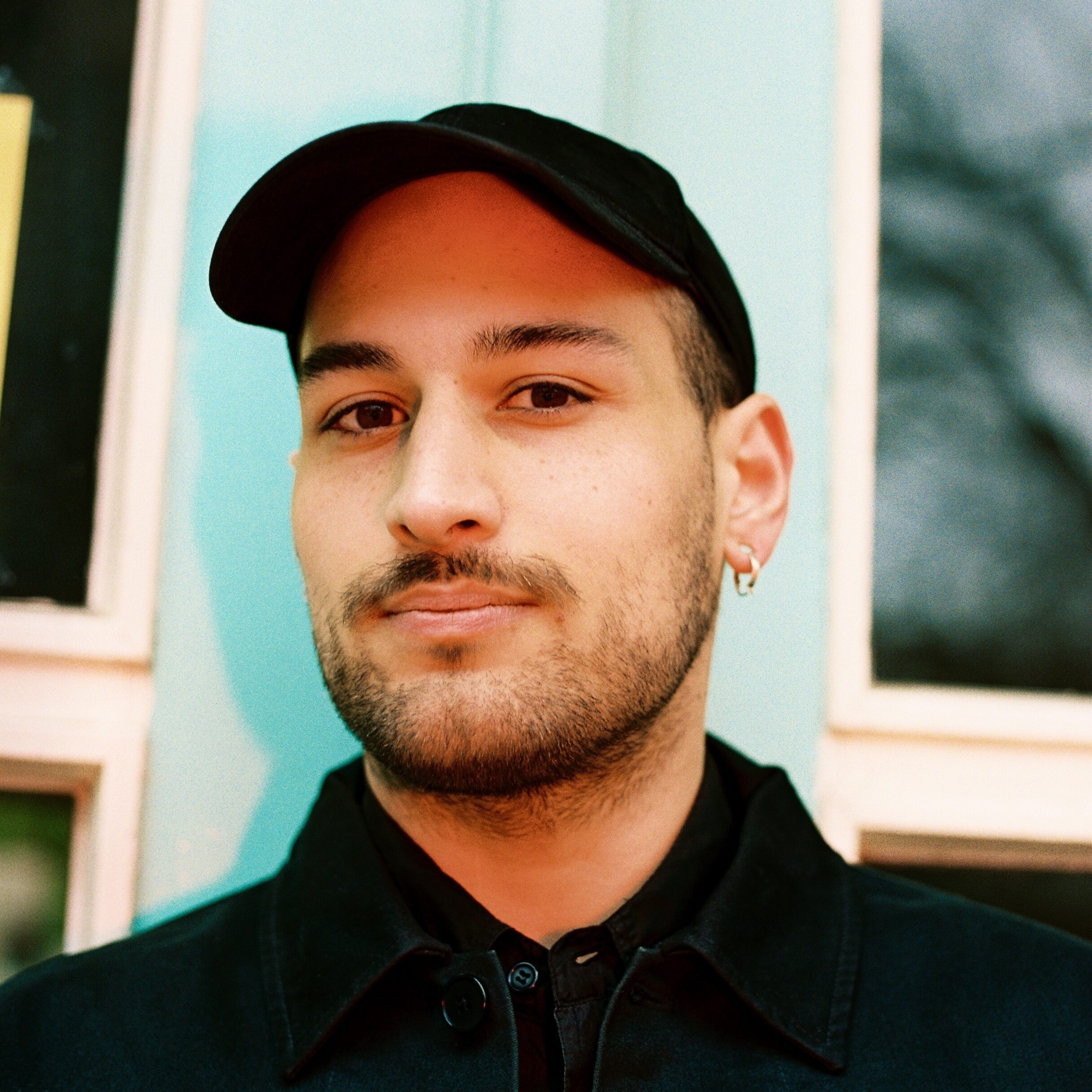 Portrait von einer männlich gesehen Person mit schwarzem Hemd und Cap